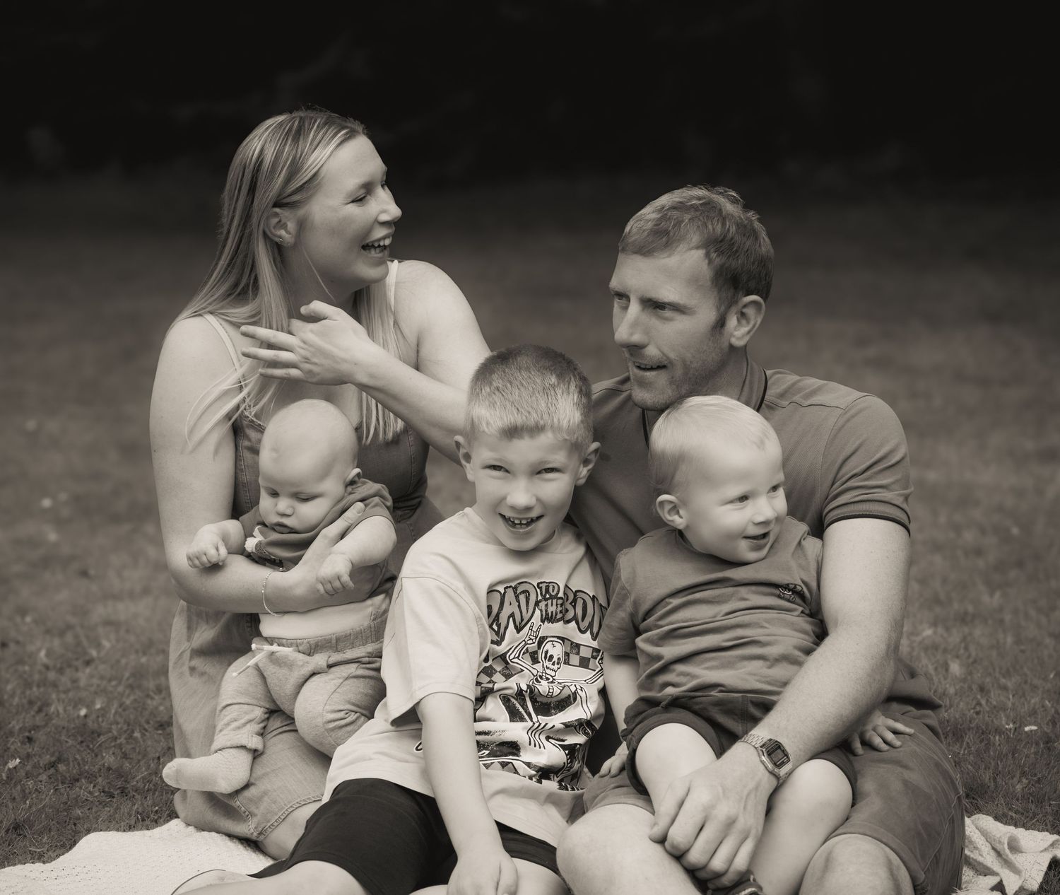 A candid black and white family portrait on grass.