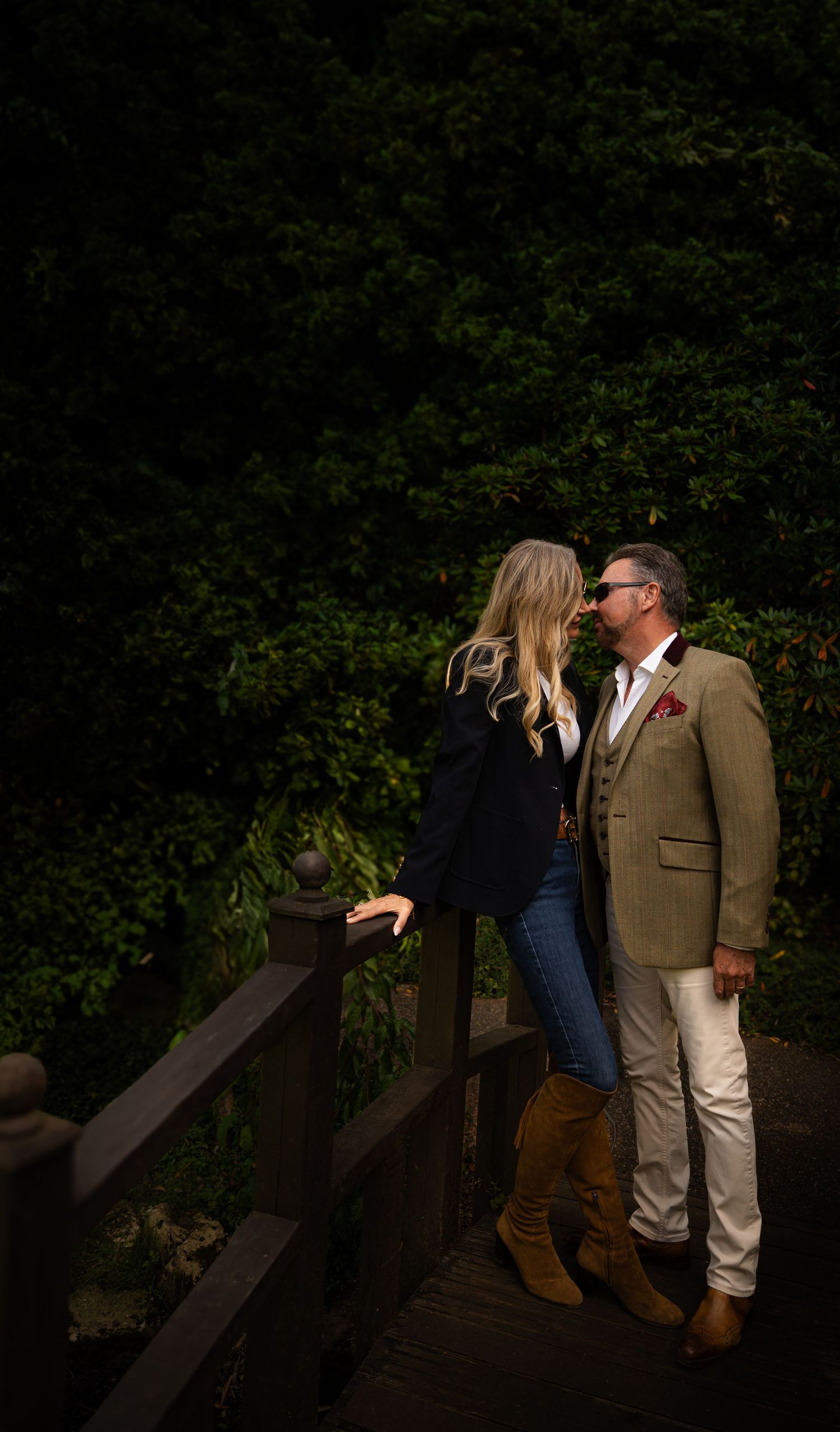 Romantic couple sharing intimate moments on a wooden bridge at dusk.