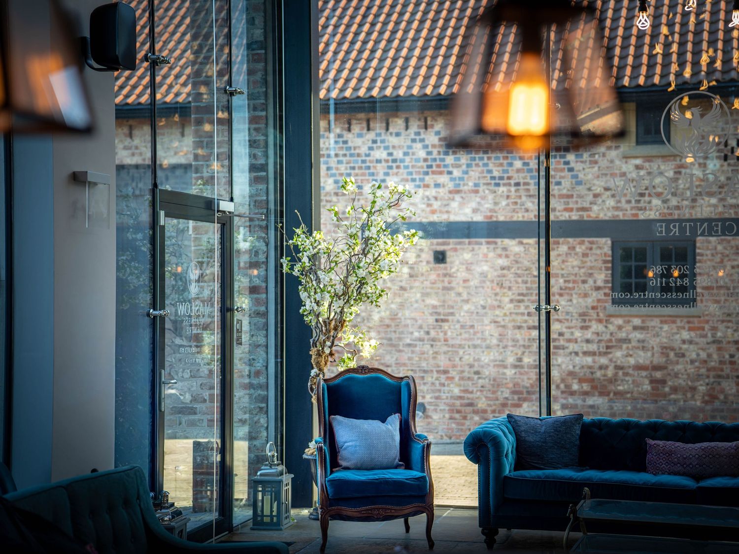 Vintage blue armchair and sofa in an industrial loft space with exposed brick walls and warm lighting.