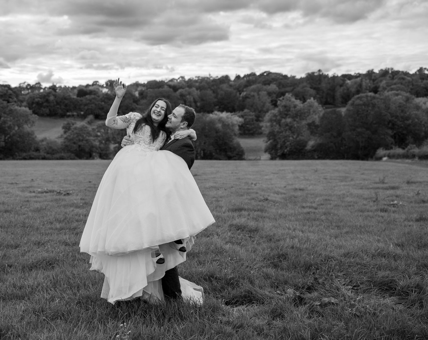 A dramatic black and white landscape of a couple crossing an open field.