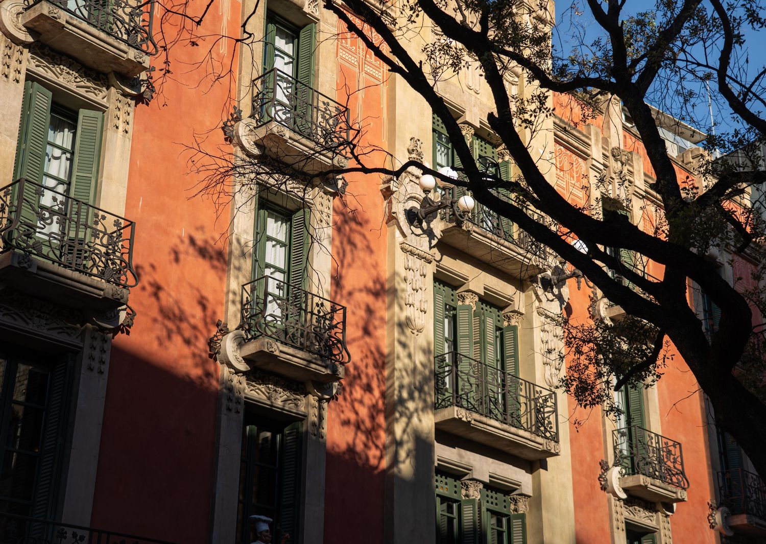 Orange sunlight illuminates historic building facades with ornate balconies and architecture.