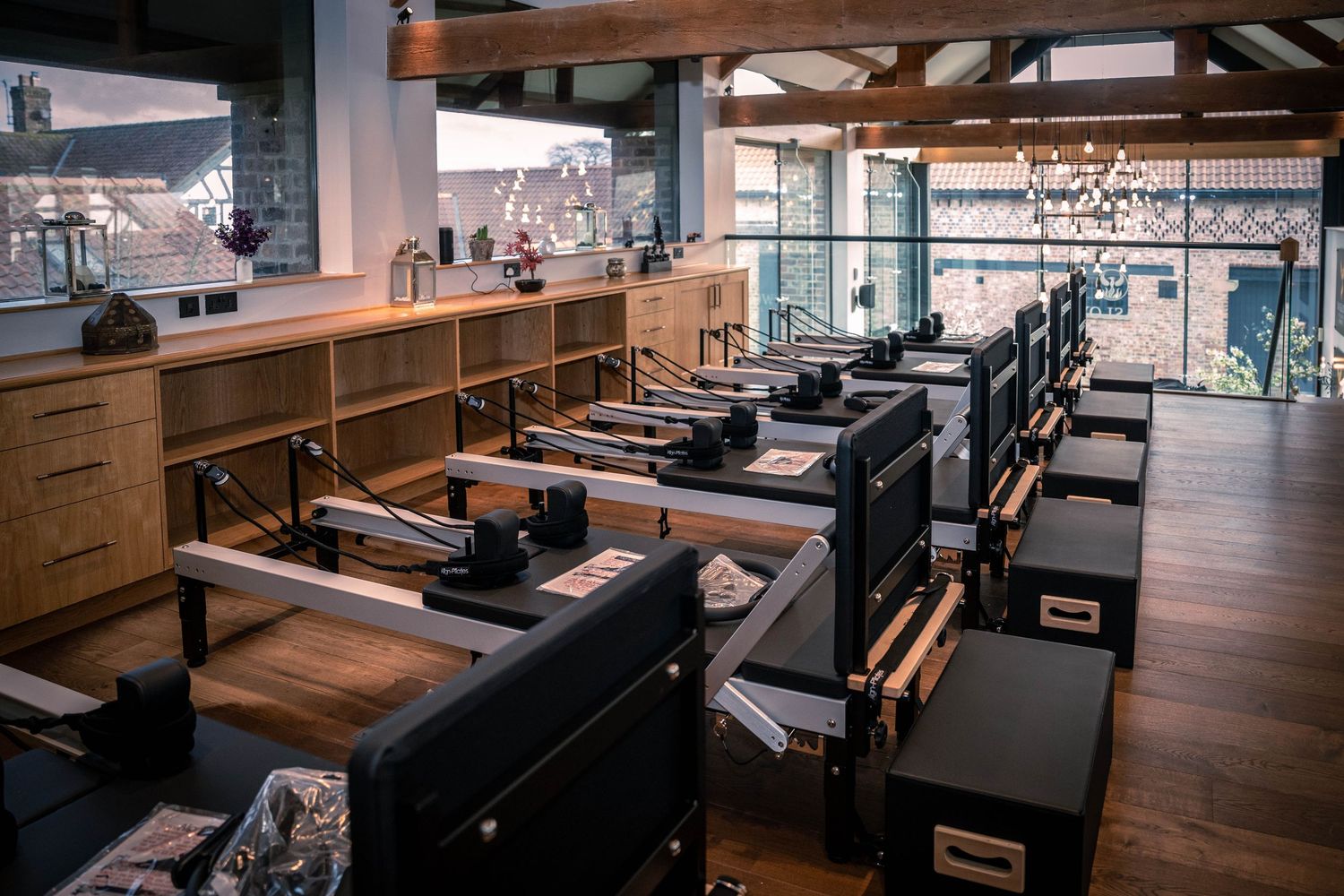 Modern fitness studio with rows of pilates reformer machines and wooden accents.