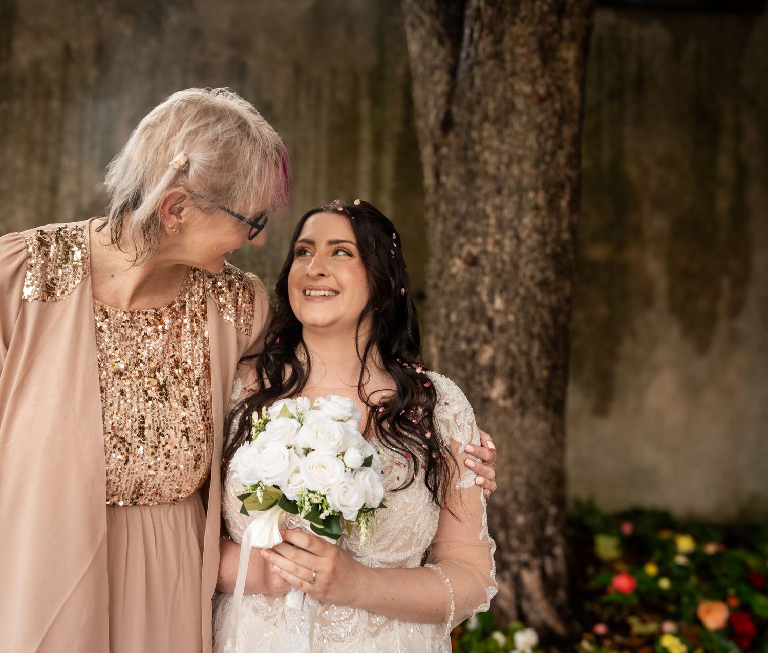 A row of bridesmaids in blush pink dresses stand together holding white floral bouquets at an elegant wedding.