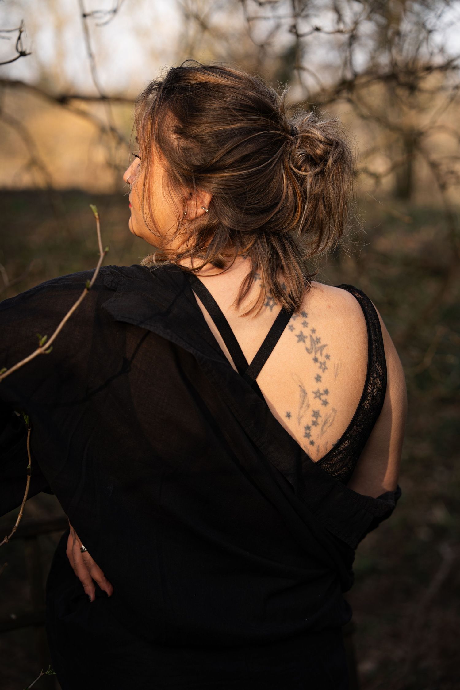 A silhouetted figure with a delicate floral tattoo visible in golden sunset light.