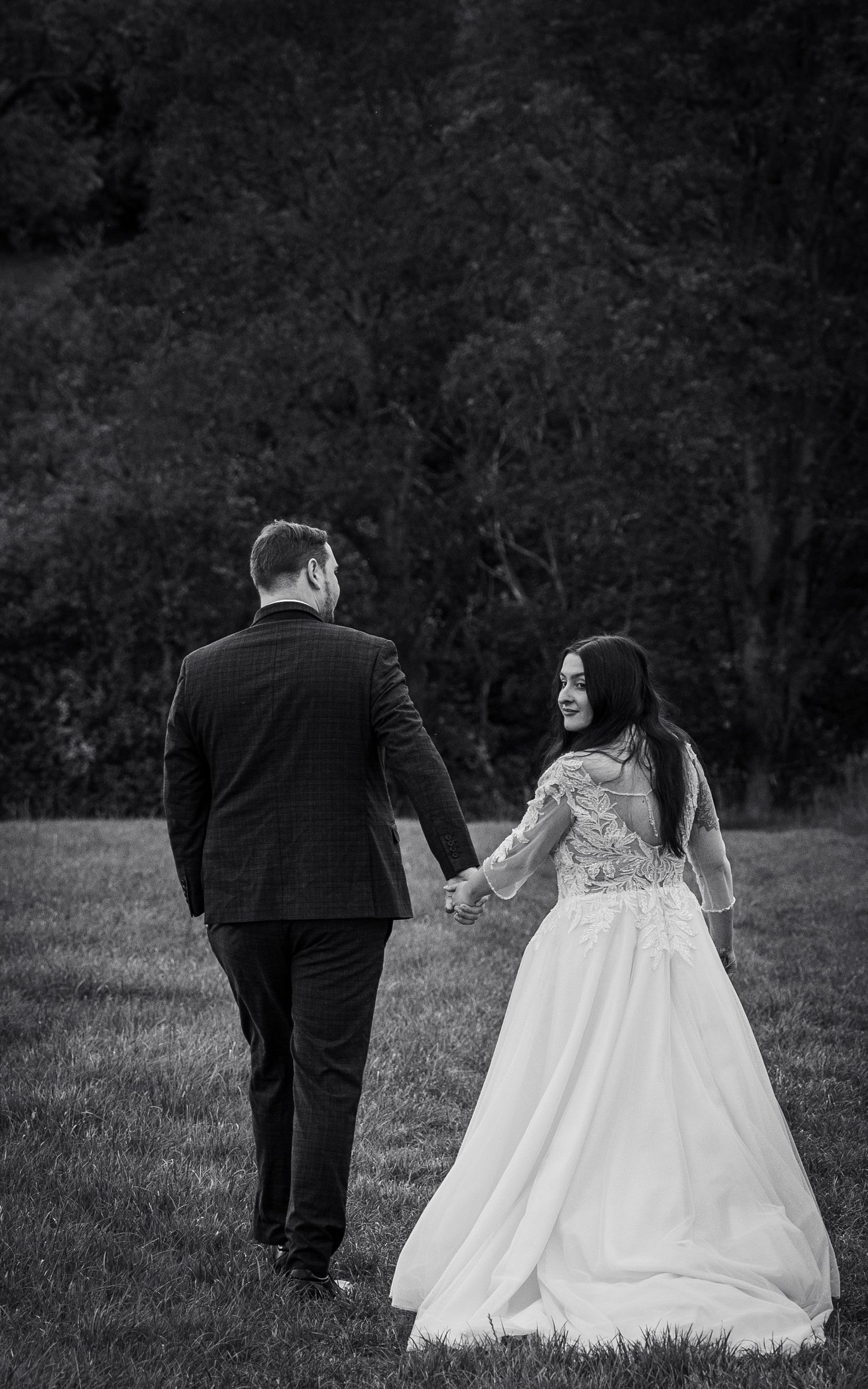 Wedding couple walking together through a scenic field in black and white.