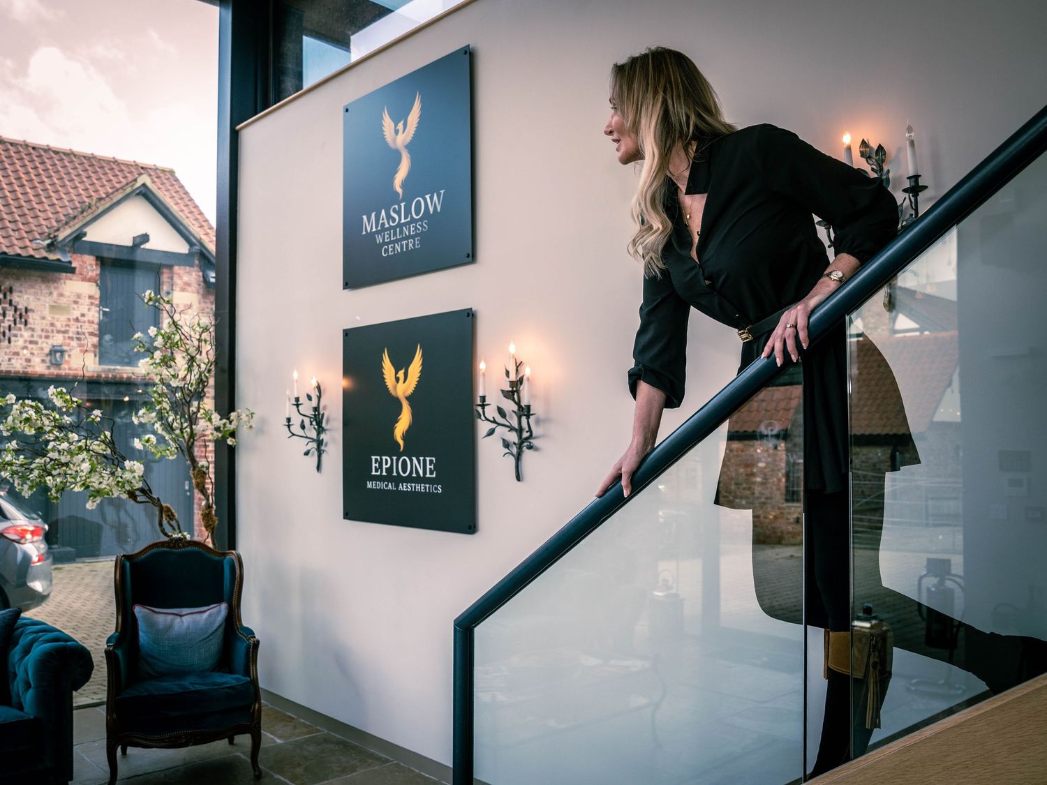 A person walks up a modern staircase with black railings and white walls adorned with artwork.