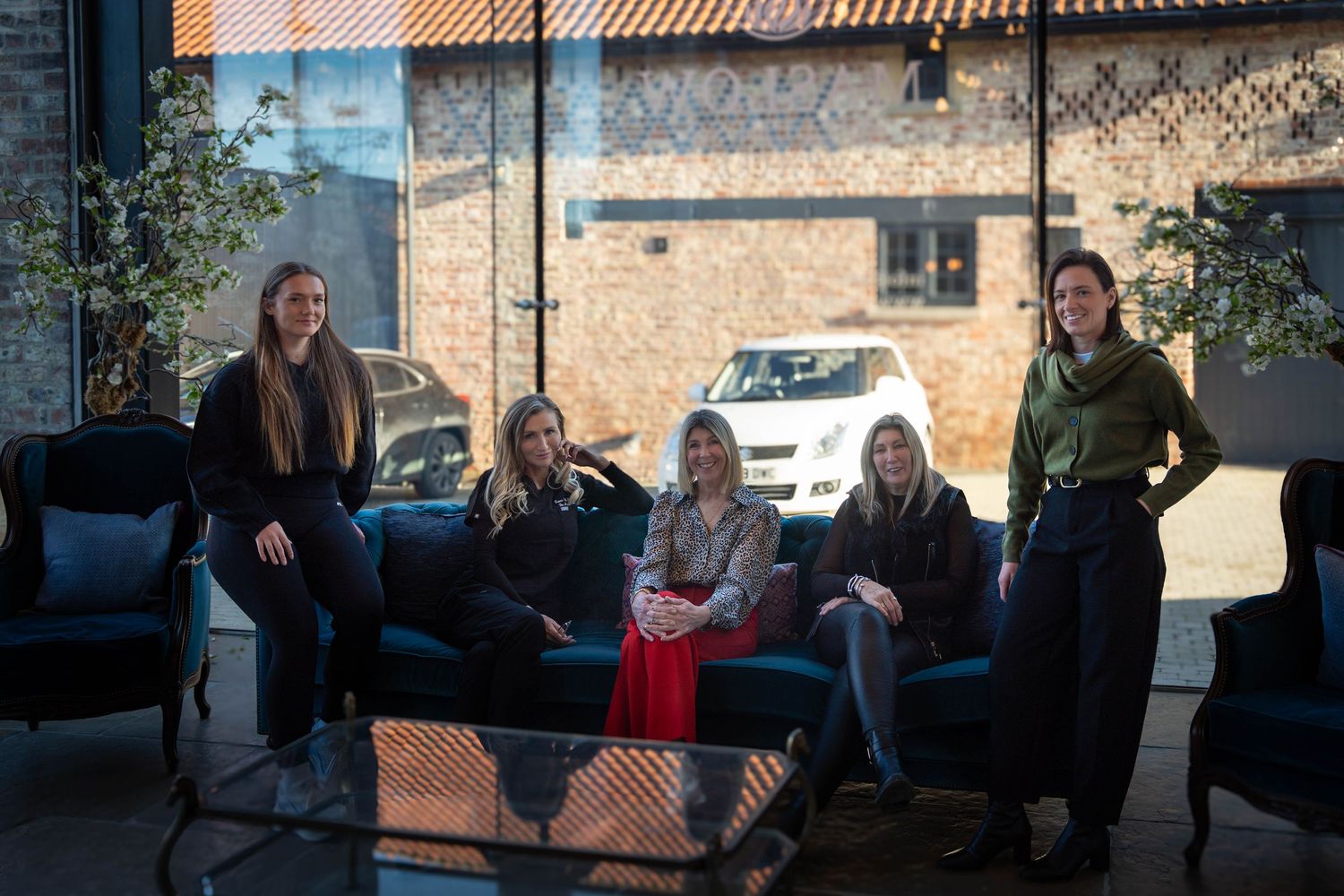 A group of people sitting together on outdoor patio furniture at a modern building.