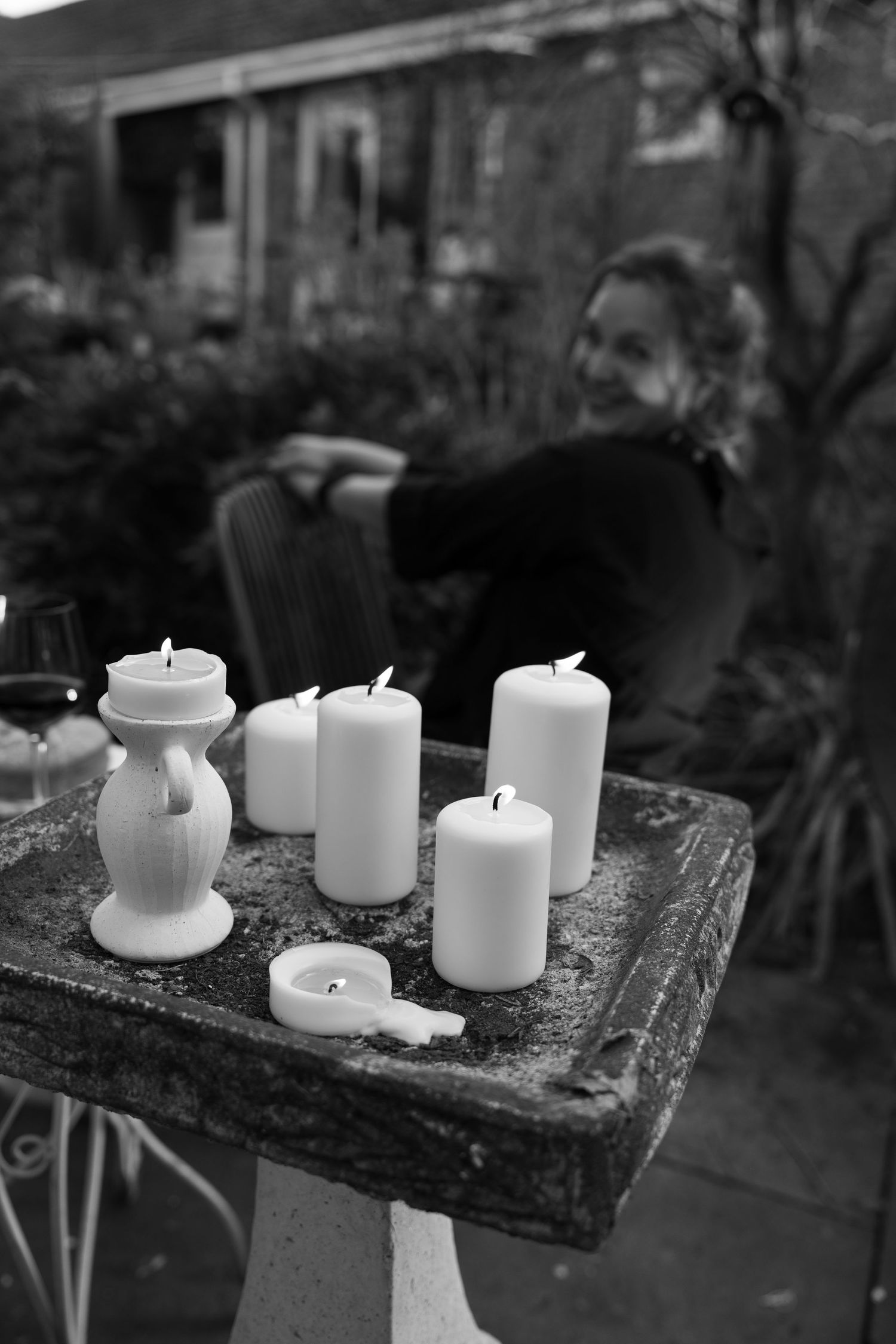 White candles arranged on a rustic wooden surface in black and white photography.