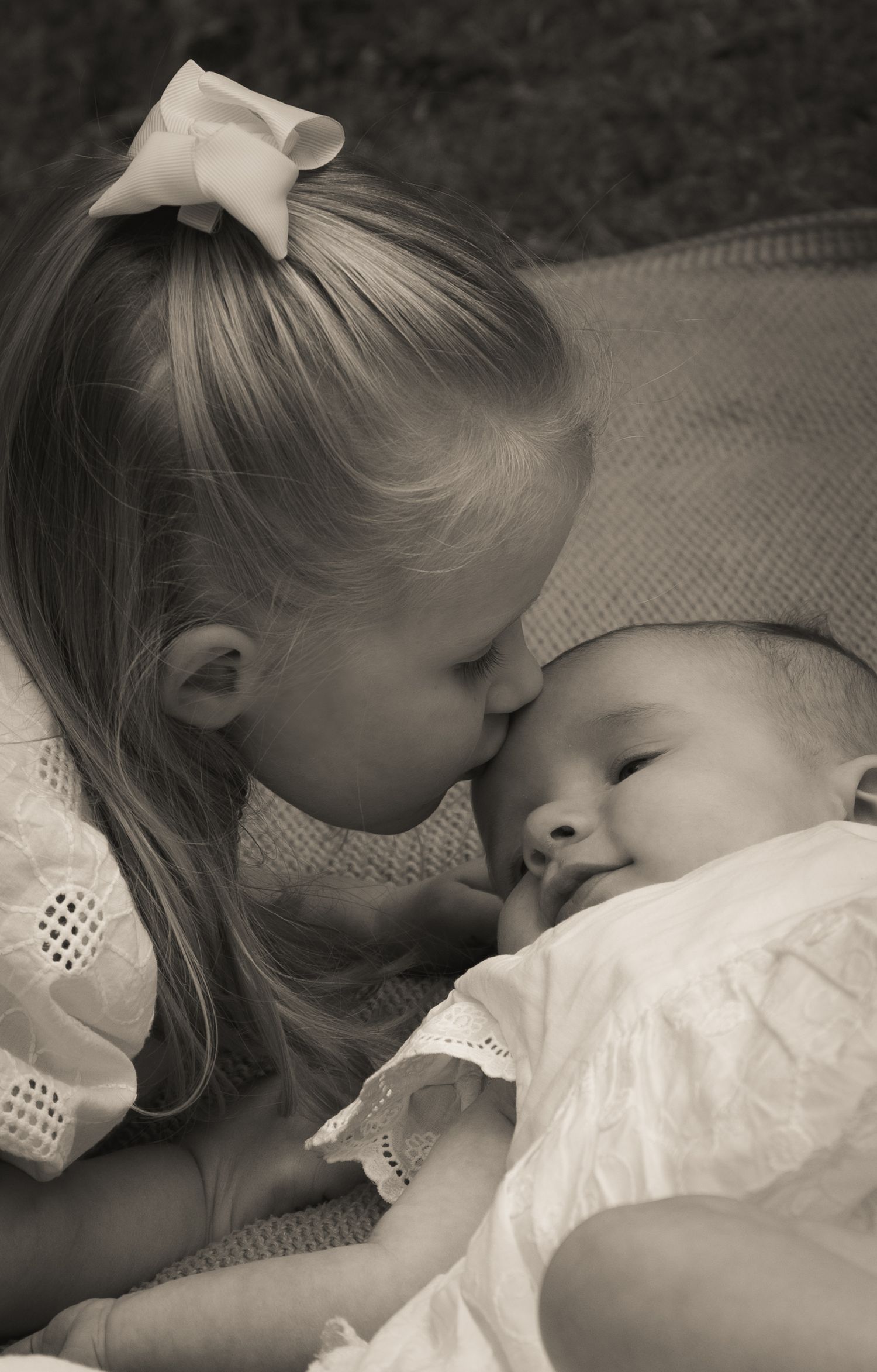 Tender black and white moments of siblings sharing gentle affection.
