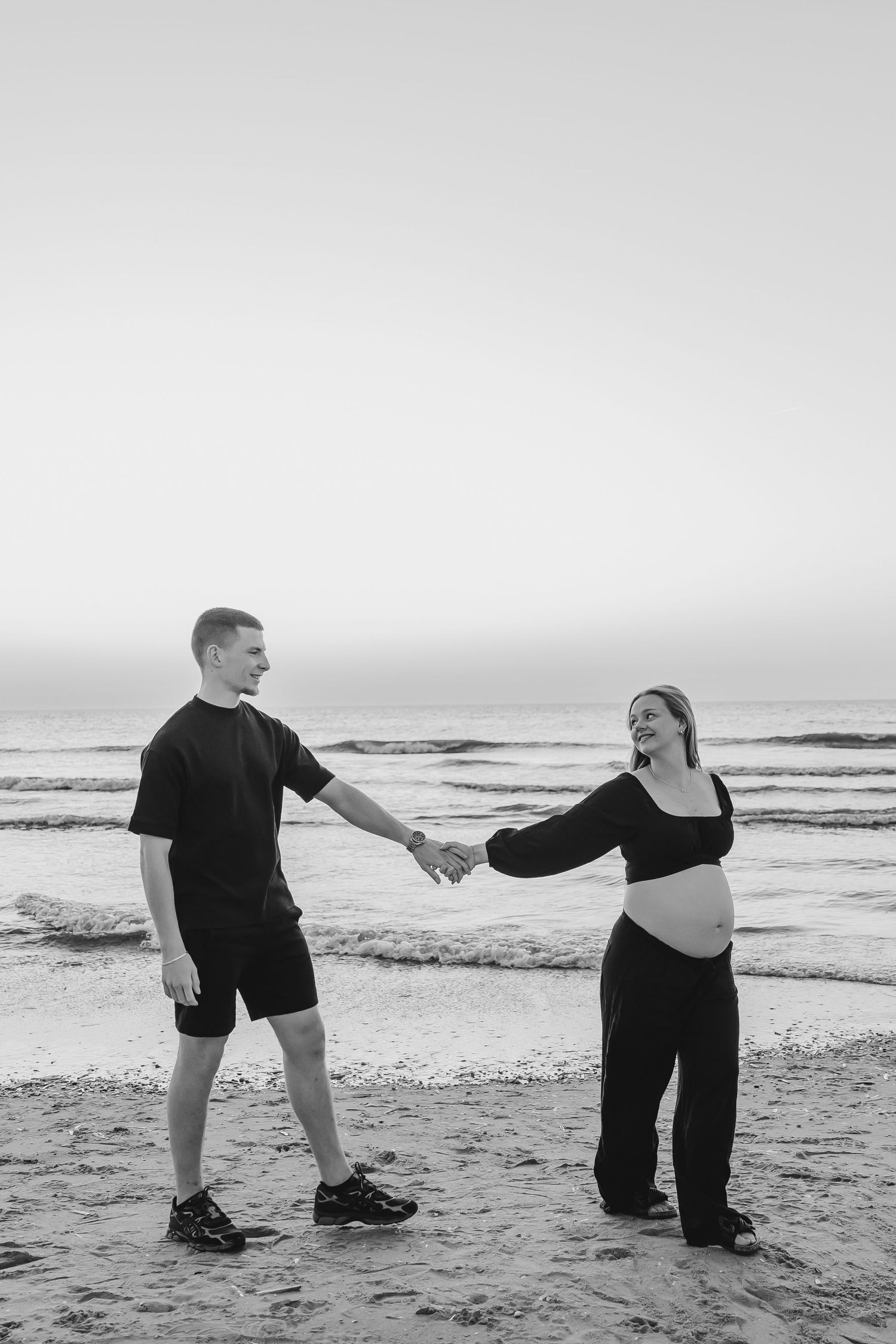 Koppel geeft elkaar een kus tijdens een fotoshoot op het strand bij zonsondergang.