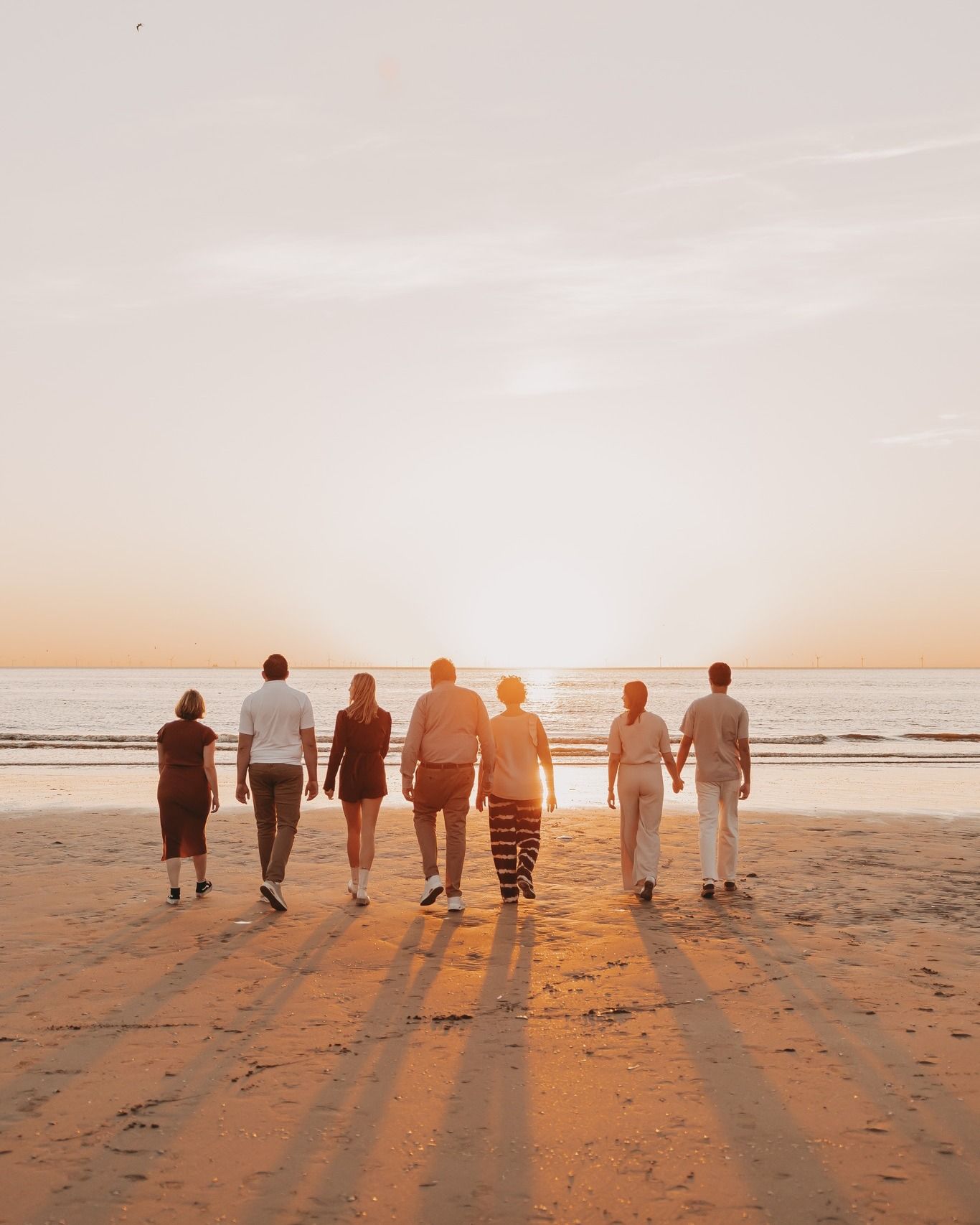 Een gezin wandelend op het strand met zonsondergang.