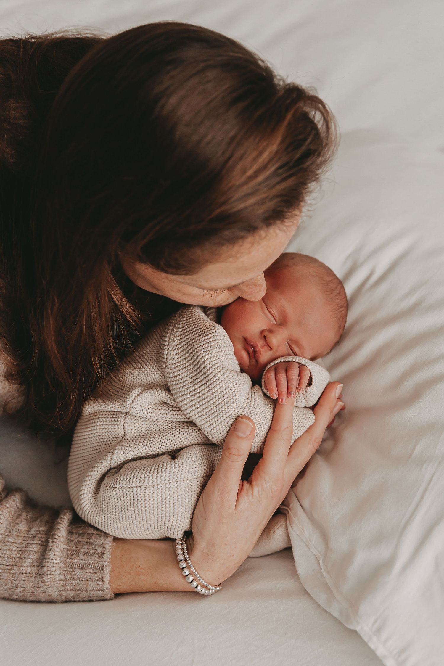 Een mama die haar newborn baby een kus geeft tijdens een newborn fotoshoot.