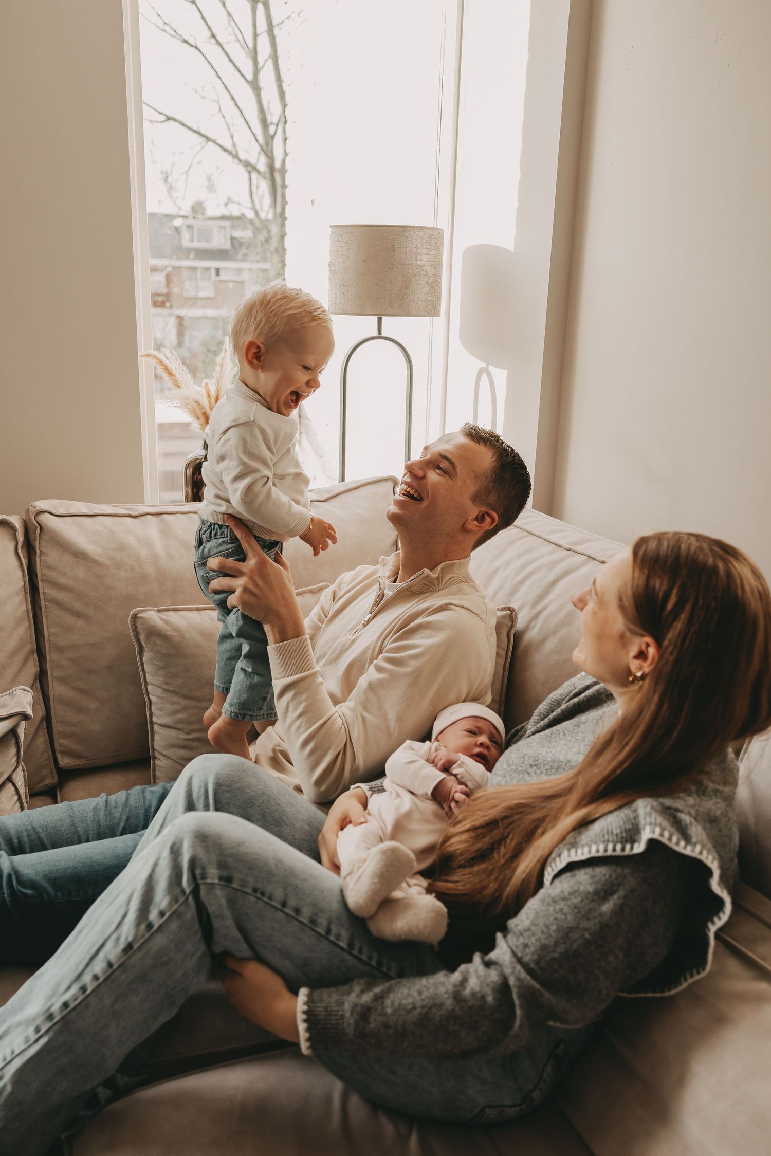 Een gezin in de woonkamer tijdens een newborn fotoshoot.