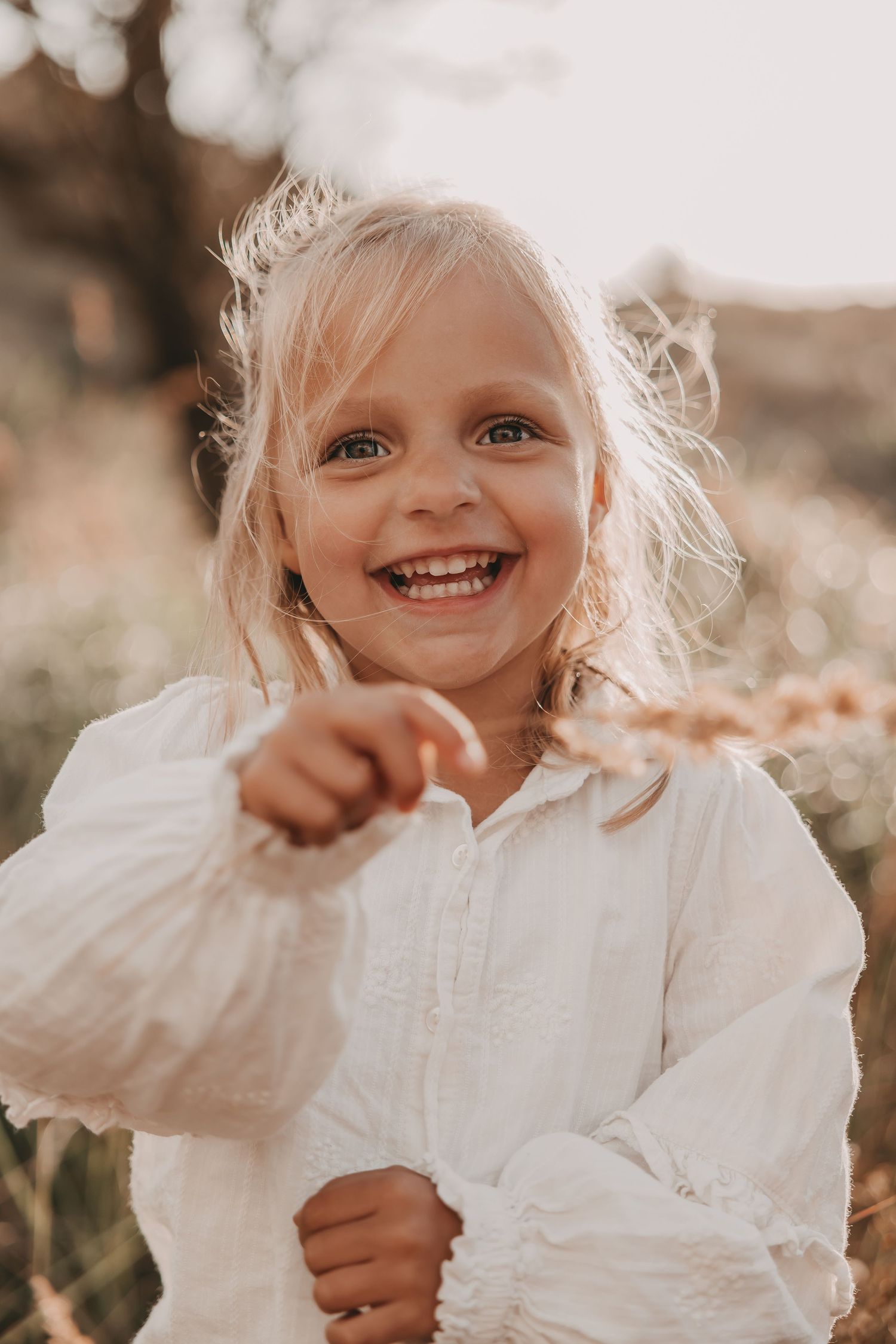 Een meisje plukt gras in de duinen tijdens een fotoshoot.