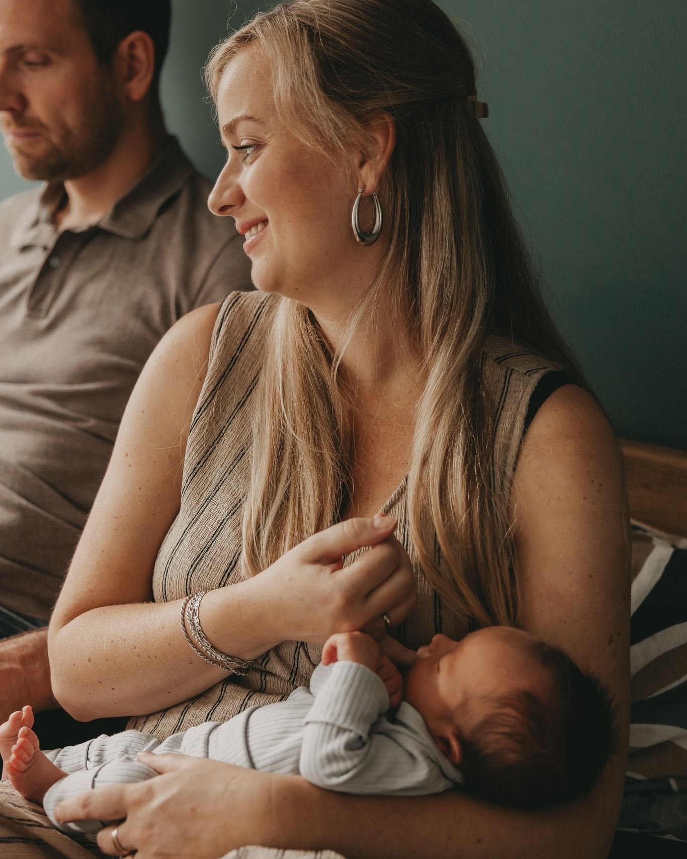 Een mama die haar baby troost op bed tijdens een newborn shoot.