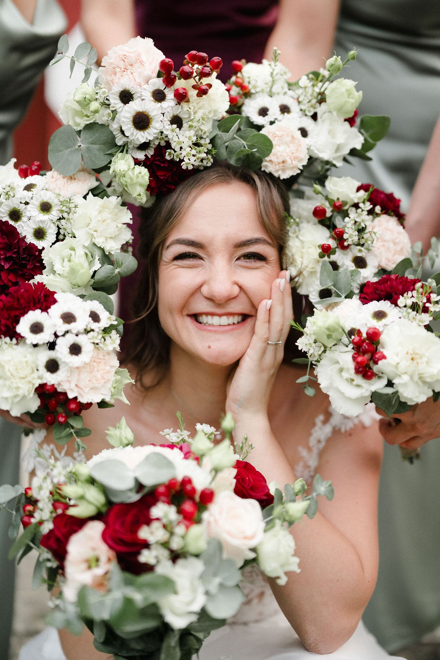 Floral crown made of white anemones, red roses and greenery adorns a festive wedding look.