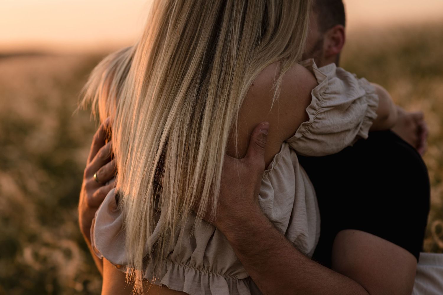 Silhouetted couple embracing during golden hour in nature.