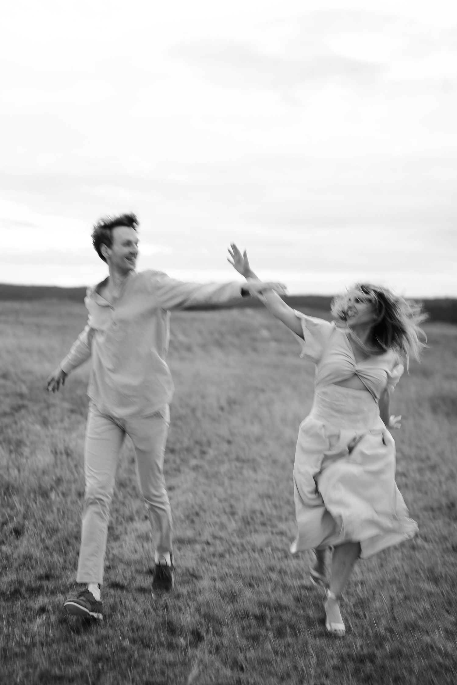 Black and white photos of couple dancing and jumping playfully in an open field.