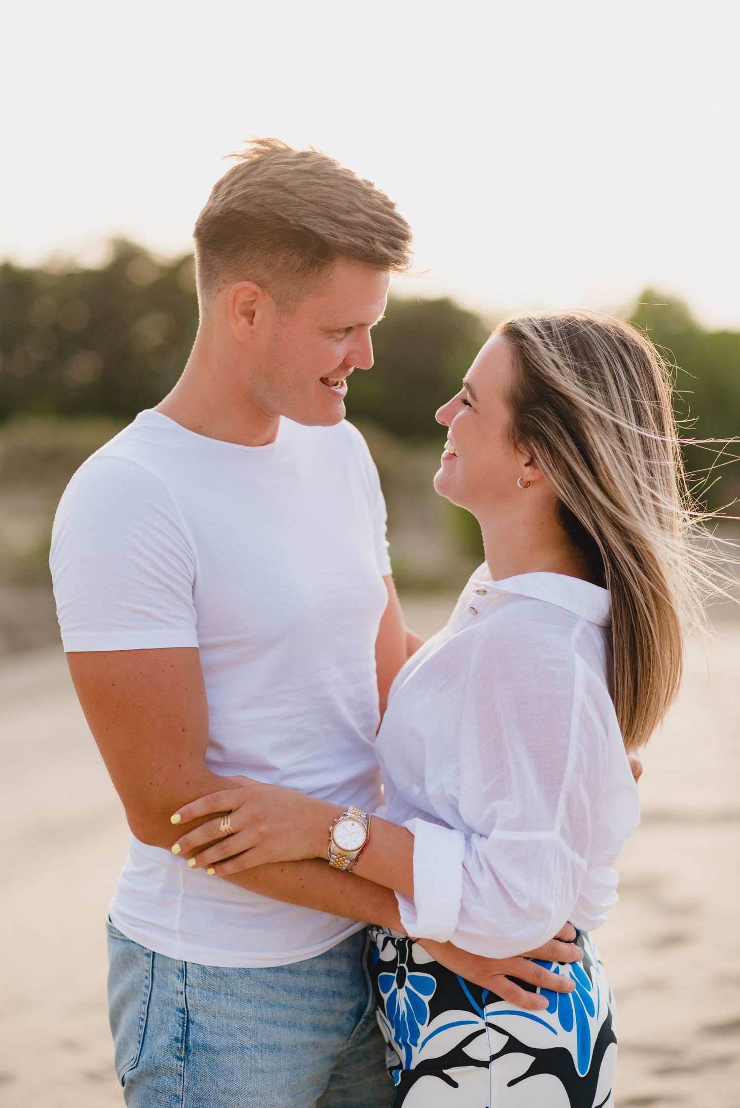 Casual couple portrait on beach with white t-shirt and patterned skirt.