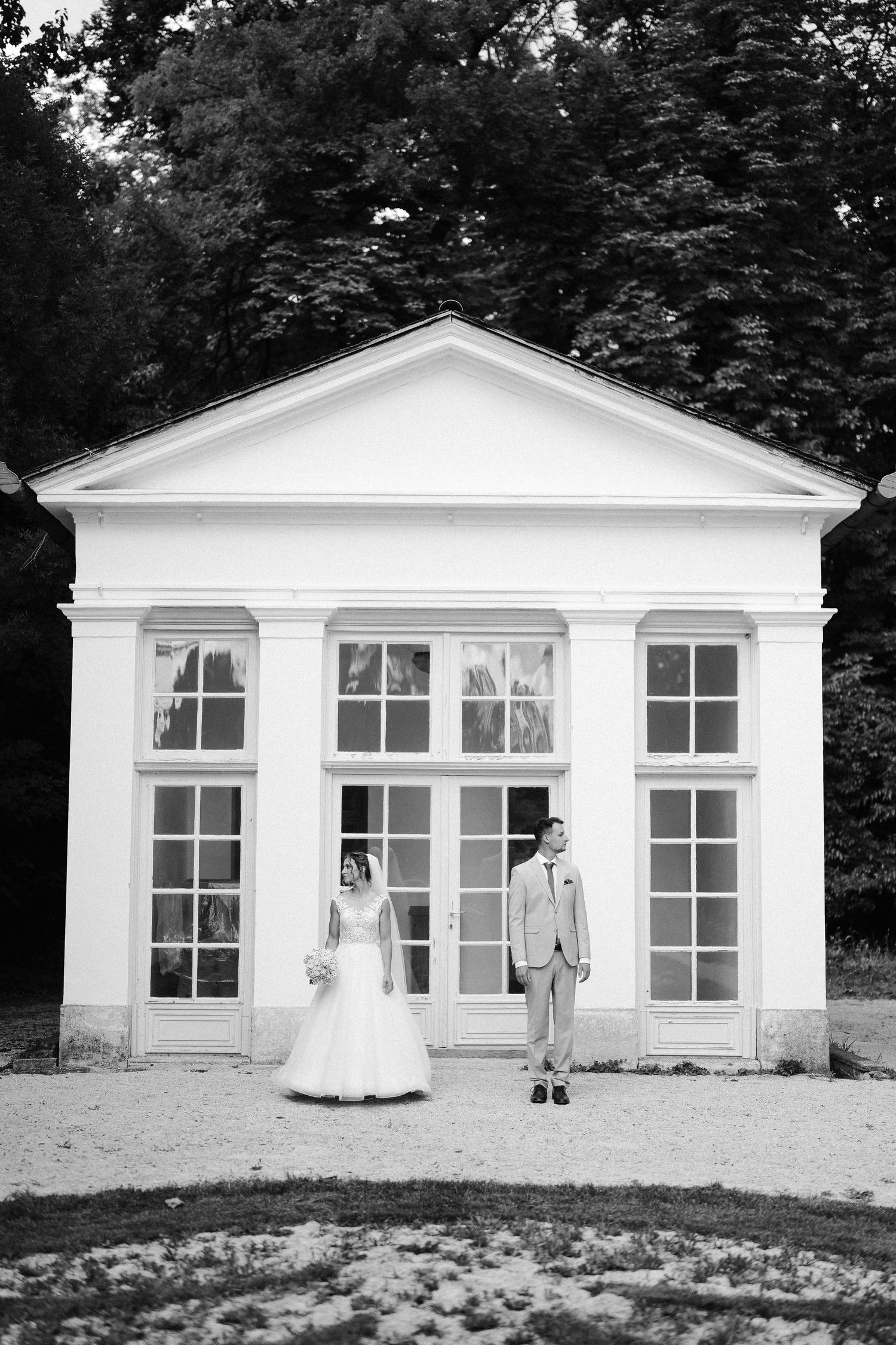 Black and white series of couple posing in front of white pavilion building.