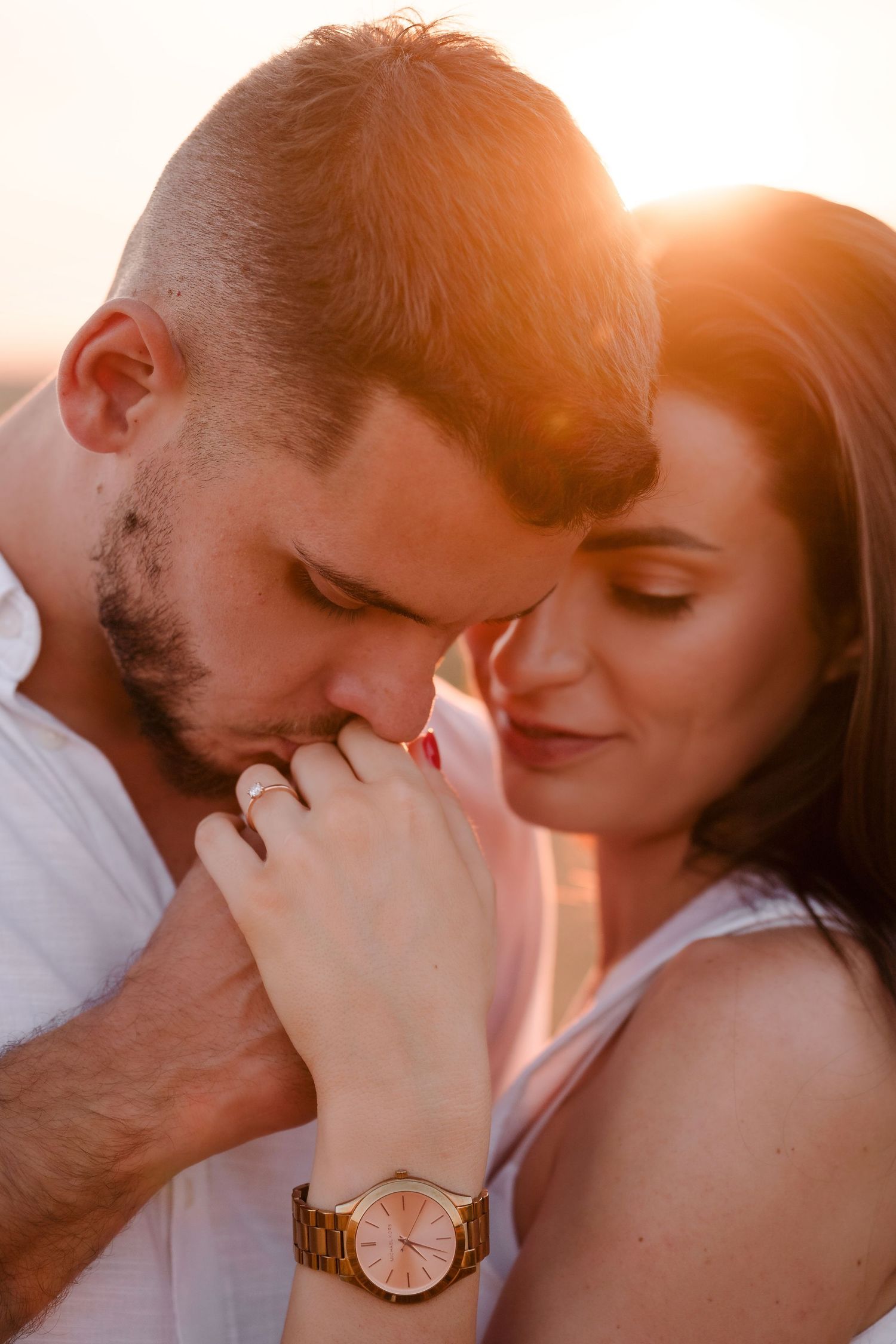 Intimate couple's portrait at sunset with golden light and a gold watch detail.