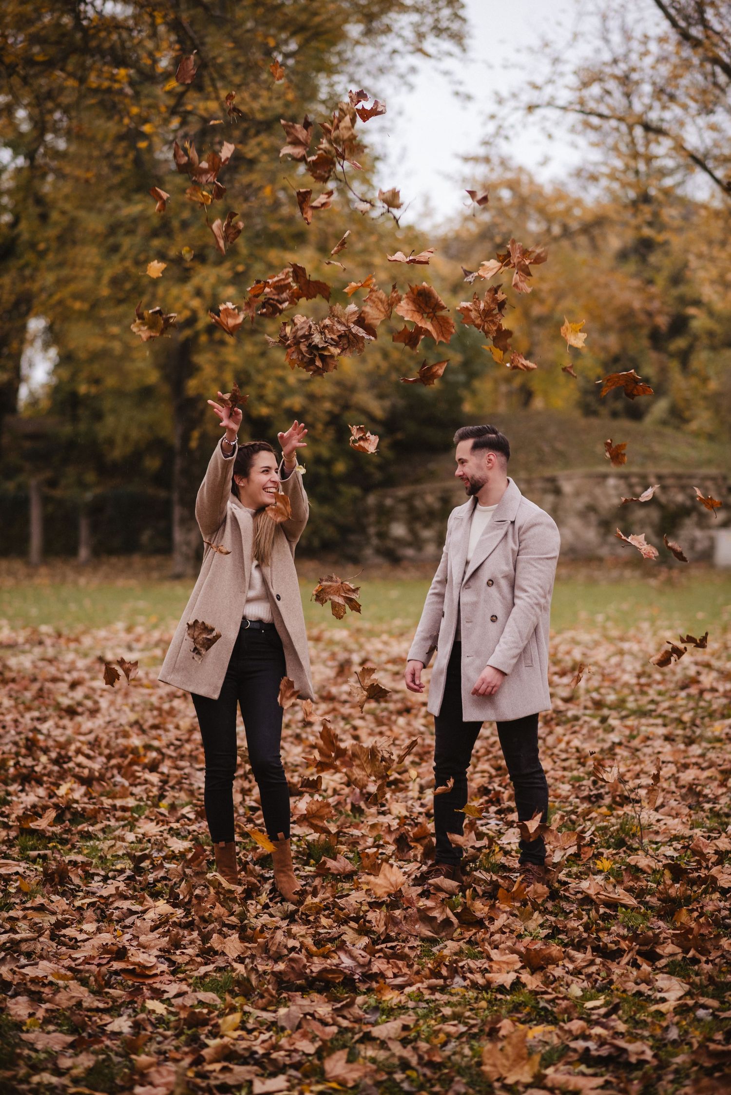Couple playing with autumn leaves in a park during fall season.