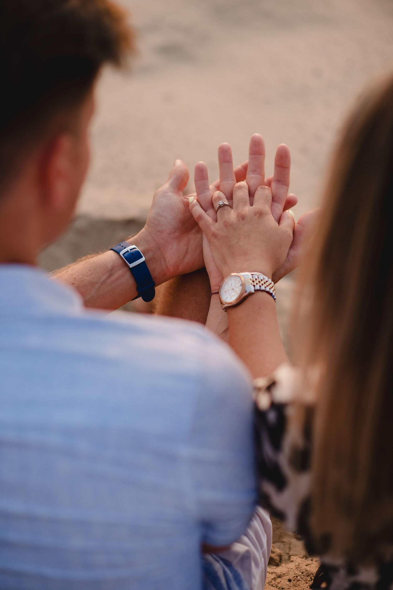 Close-up of hands showing engagement rings during sunset.