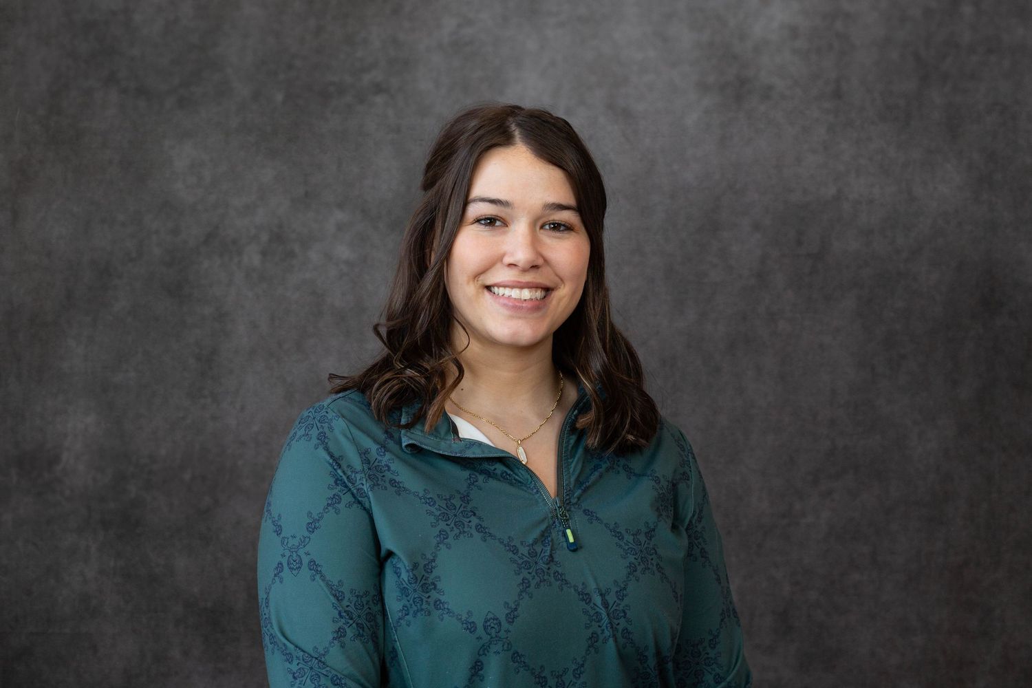 Professional headshot portrait series in black and white against textured gray background wearing teal colored top.