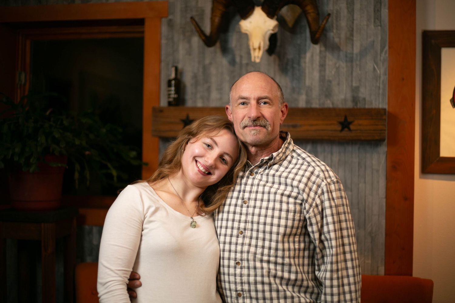A couple in casual attire poses together for a series of romantic engagement photos in a cozy indoor setting.