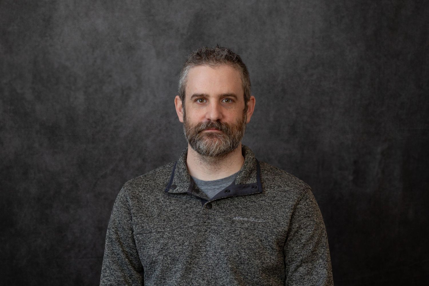 Professional headshot portraits against dark background showing different facial expressions and poses.