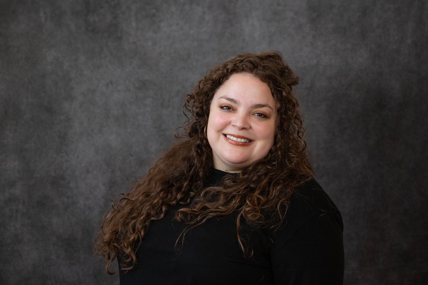 A series of black and white portraits showing someone with curly hair smiling against a dark textured backdrop.