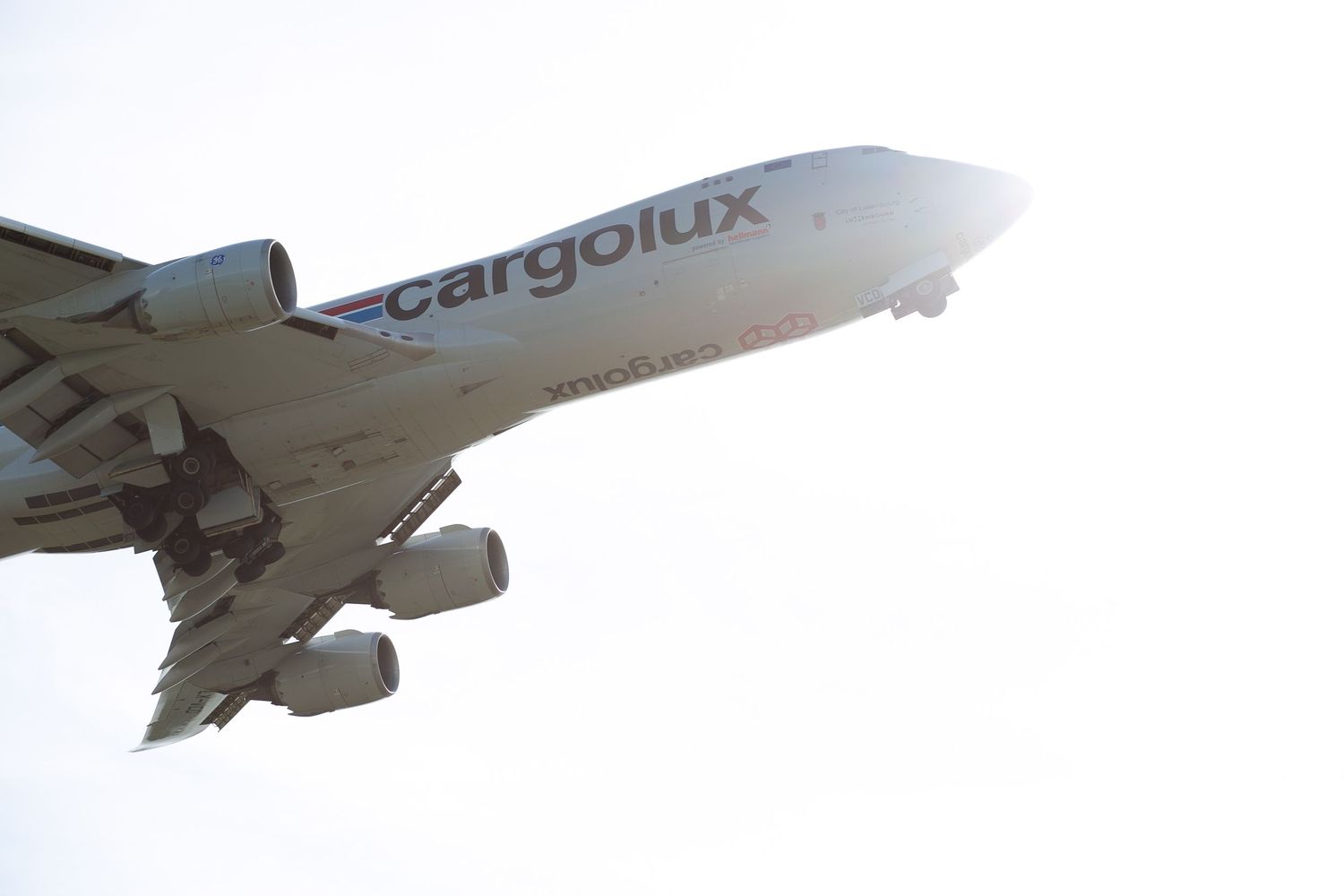 A series of white cargo aircraft flying in formation against a bright blue sky background.
