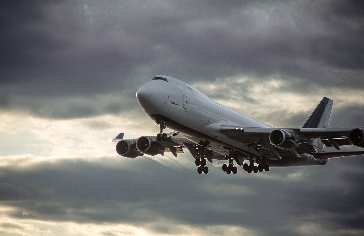 Large commercial Boeing 747 airplane taking off against dramatic stormy cloudy sky.