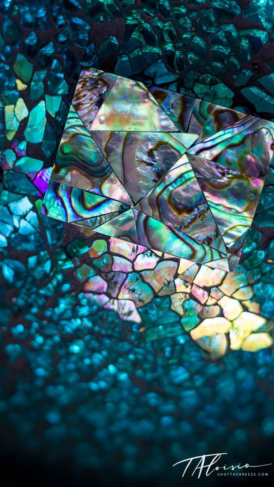 Iridescent mother of pearl texture creating a mosaic pattern in turquoise and rainbow colors.