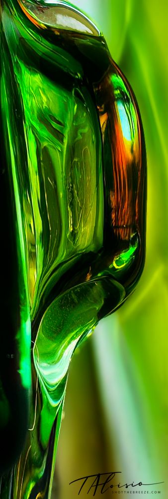 Abstract macro photograph of green glass bottle showing curved reflections and translucent effects.