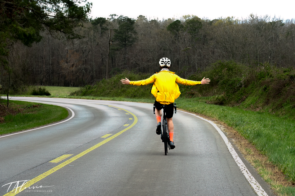 Person in bright yellow costume walking along a winding rural road through green landscape.