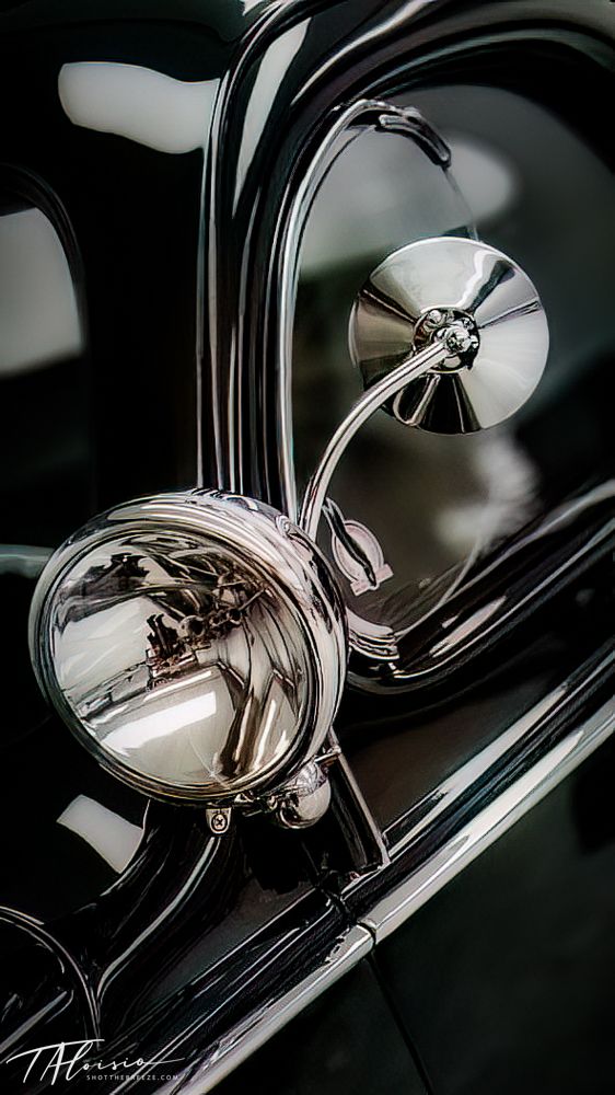 Chrome motorcycle mirrors reflecting light against dark background.