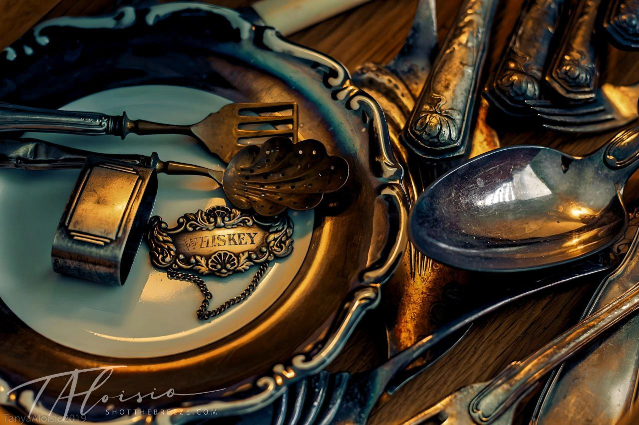 Close-up details of ornate vintage silverware and place settings in warm lighting.