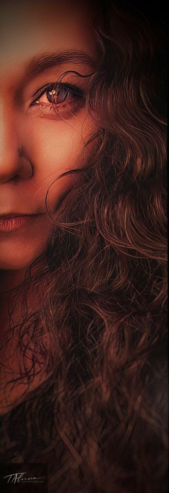 Artistic close-up portrait in warm tones with flowing dark hair creating shadow and depth.