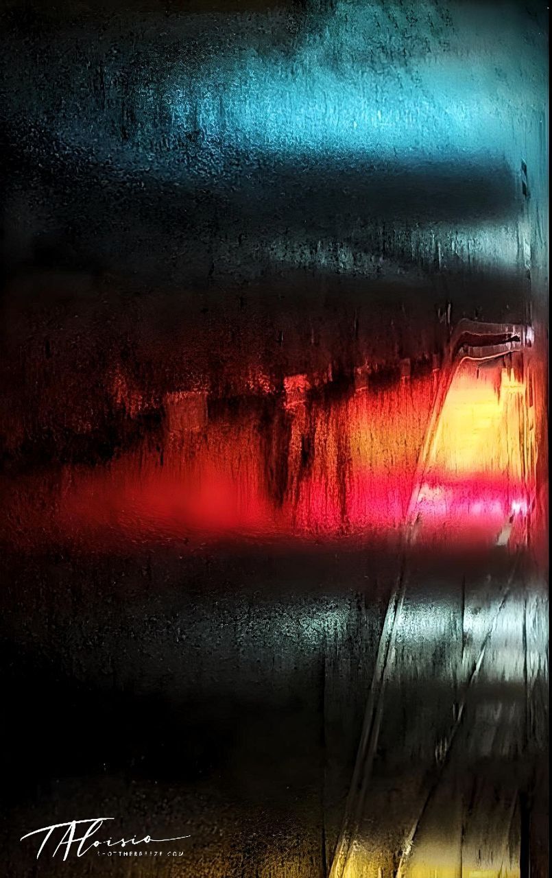 Abstract photography of city lights through wet glass creating colorful streaks.