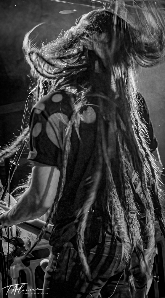Dramatic black and white sequence of performers with long hair in motion during a stage performance.