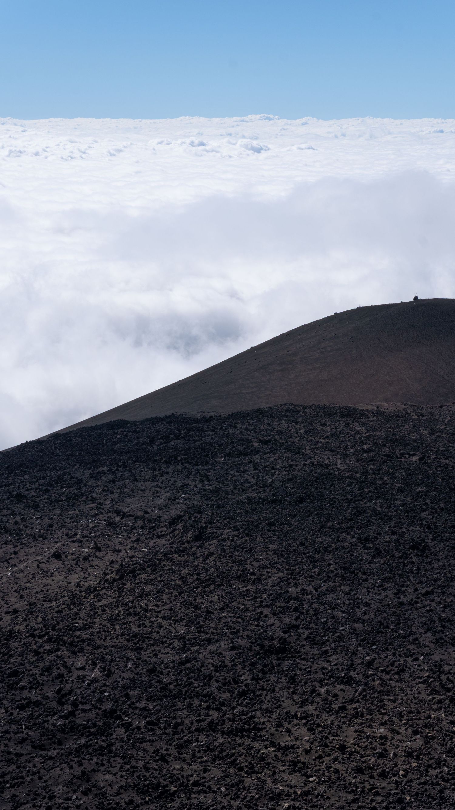 Fotografia paesaggistica, riflessiva e calma. Cratere Etna con in sfondo le nuvole del cielo.