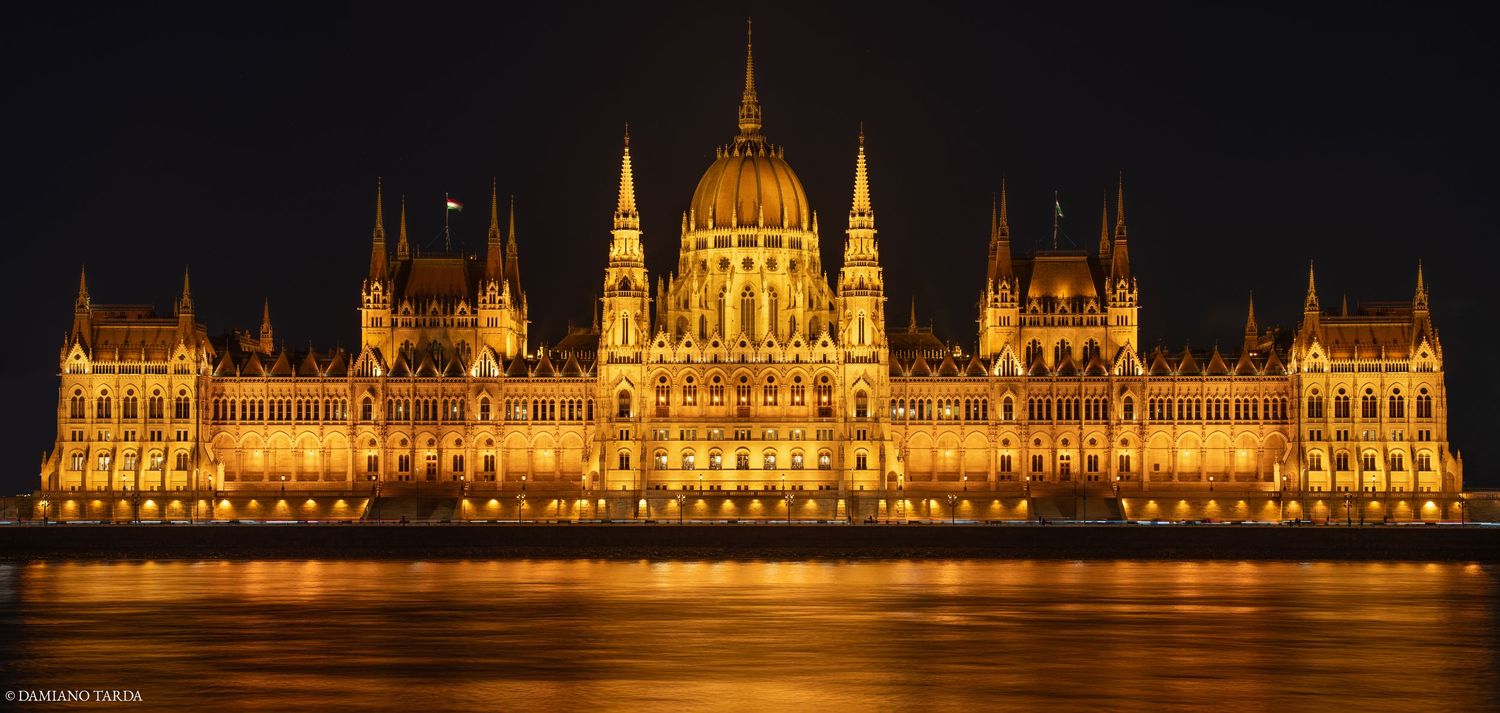 budapest notturna, parlamento illuminato con riflessi sul Danubio.