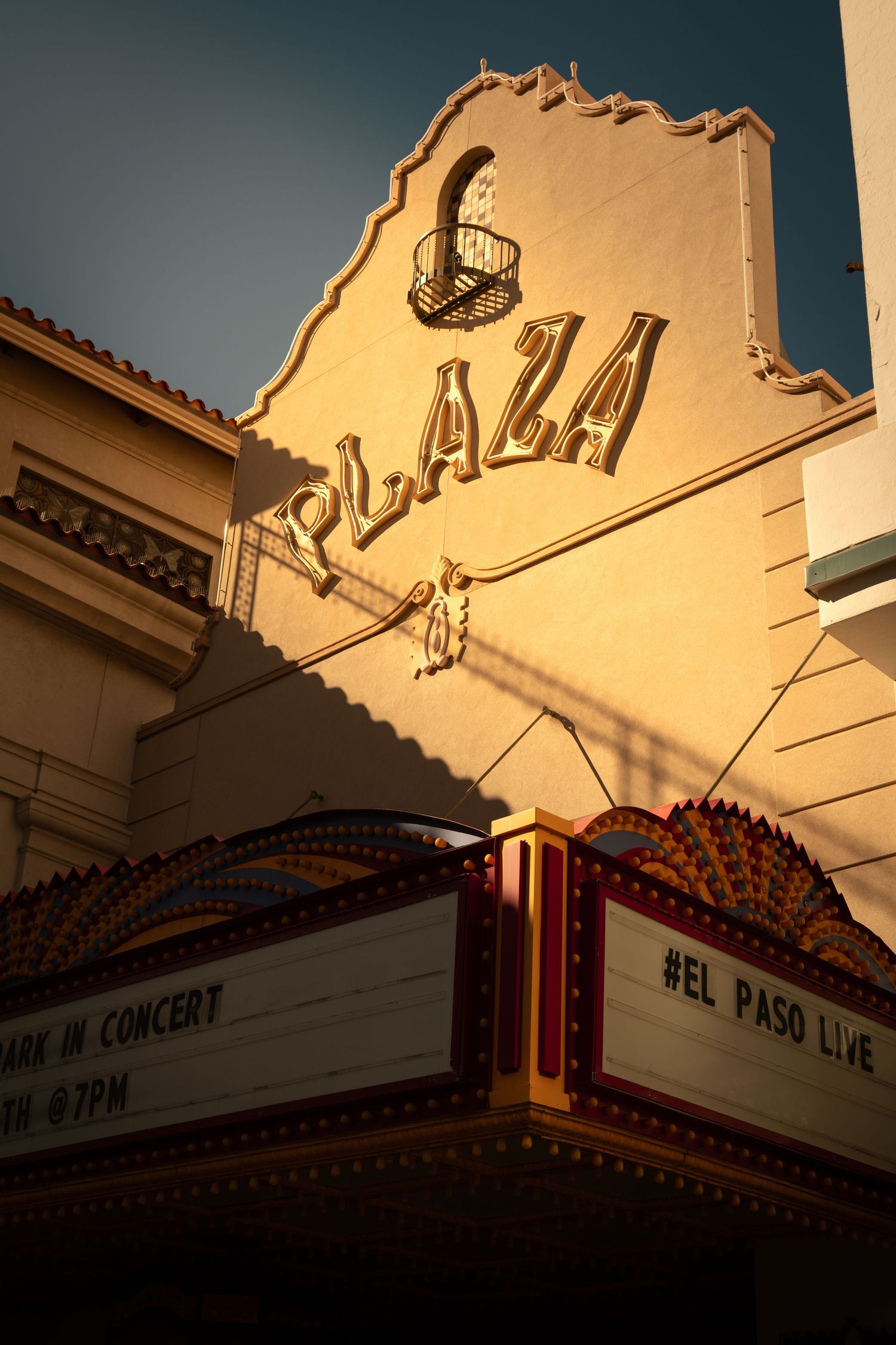 The Plaza Theater's vintage marquee and ornate Spanish Colonial facade glows warmly in golden sunlight.