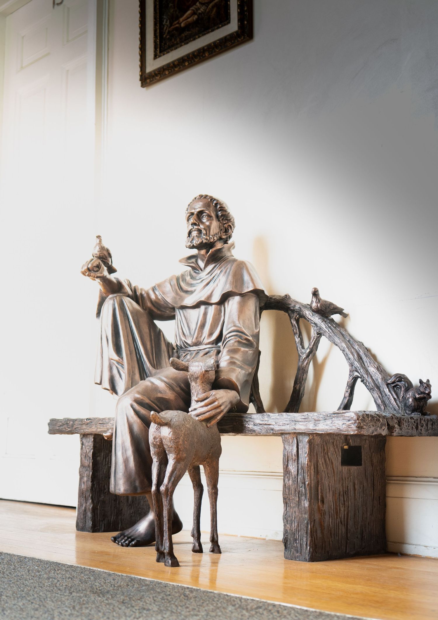 A series of sculptures showing a seated figure with a dog, displayed in a gallery setting with wooden elements.