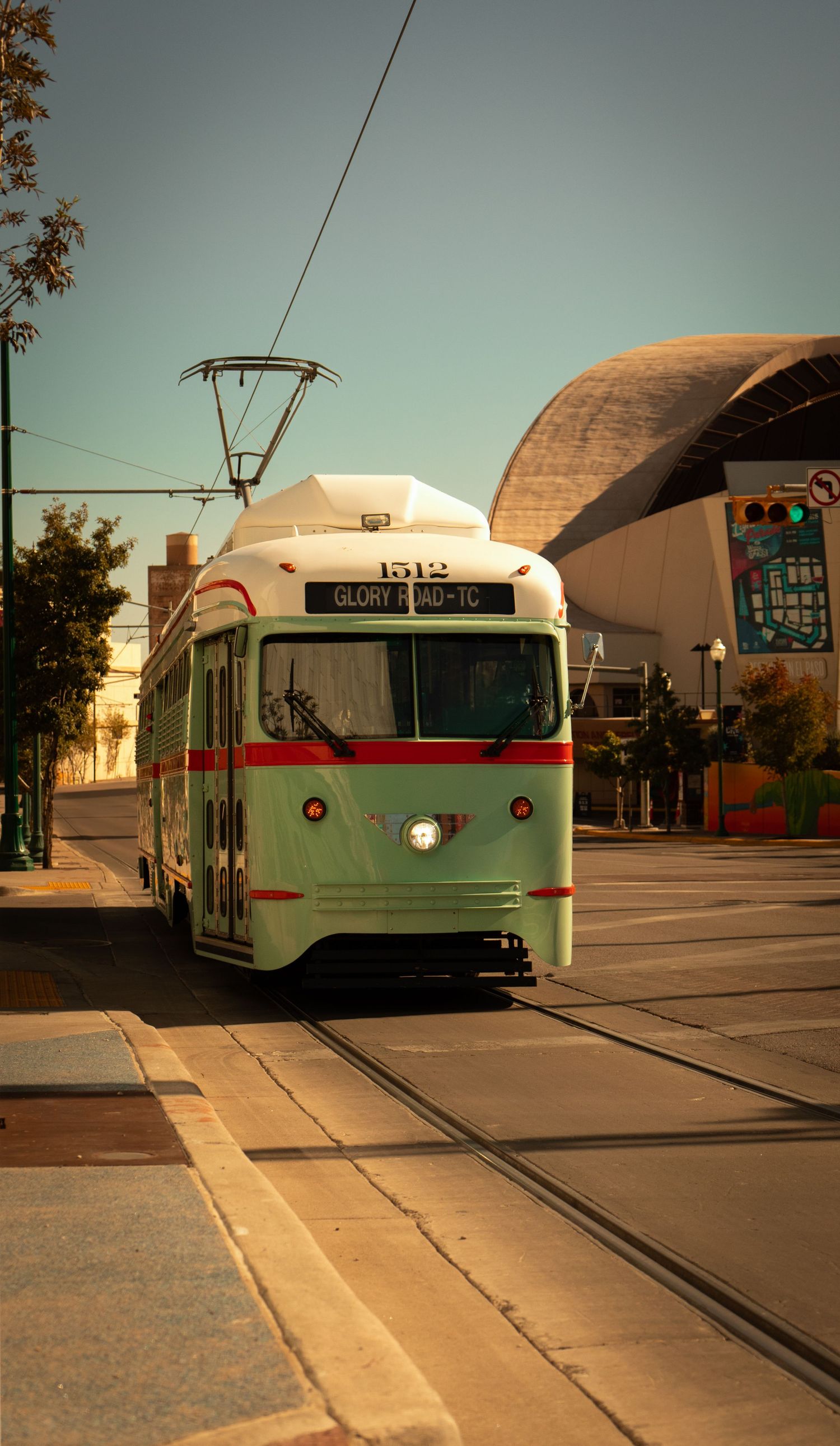 A series of vintage streetcars shown from different angles at a transit station during sunset with domed buildings in background.