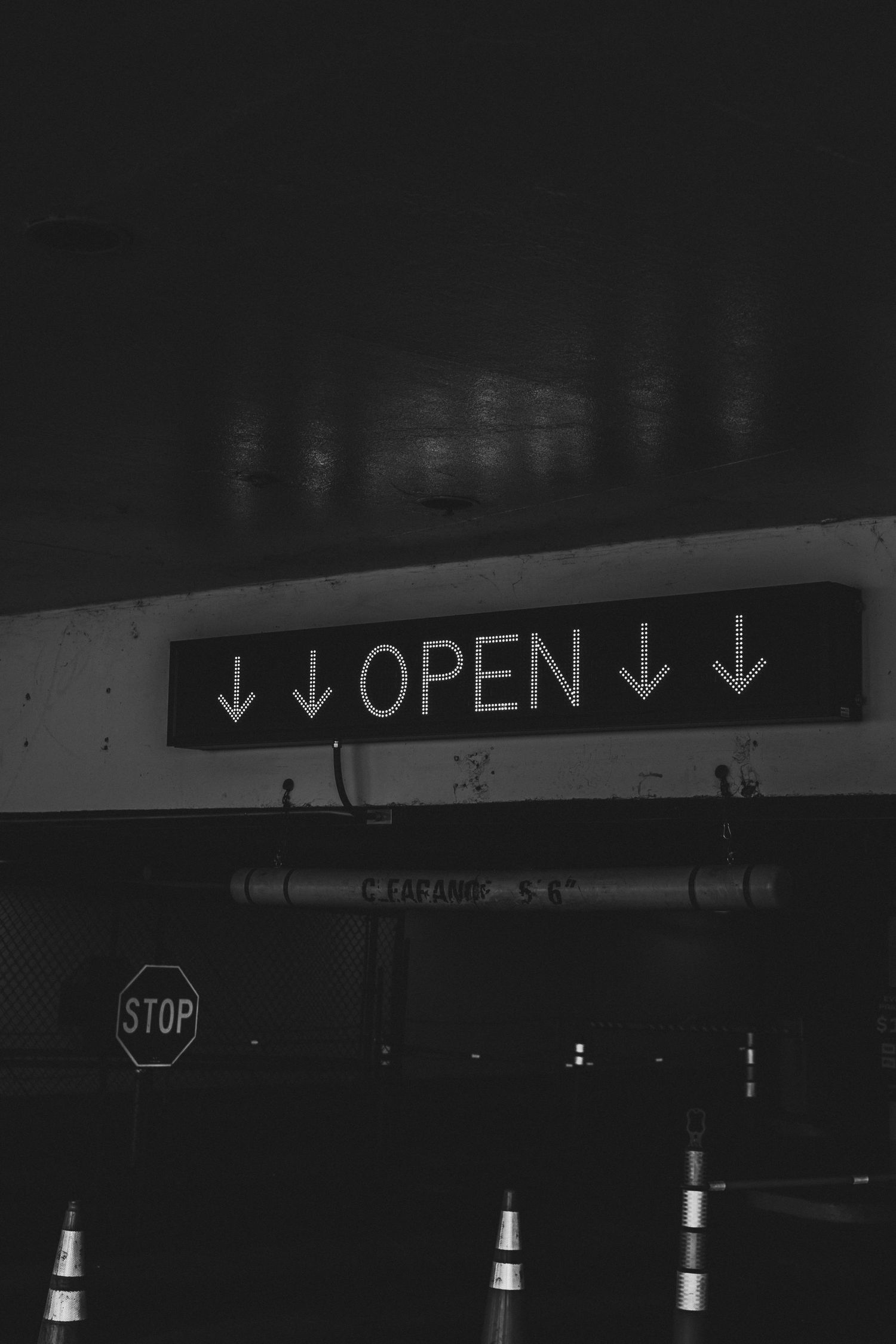 Illuminated 'OPEN' sign with downward pointing arrows glows against a dark background.