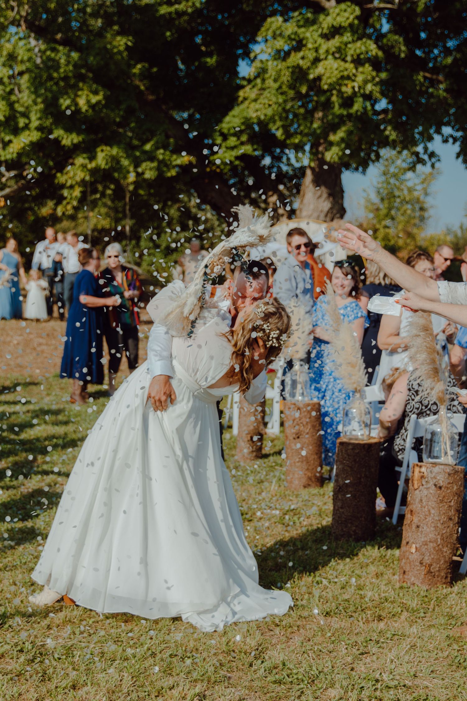 Wedding celebration with guests throwing confetti in an outdoor garden setting.