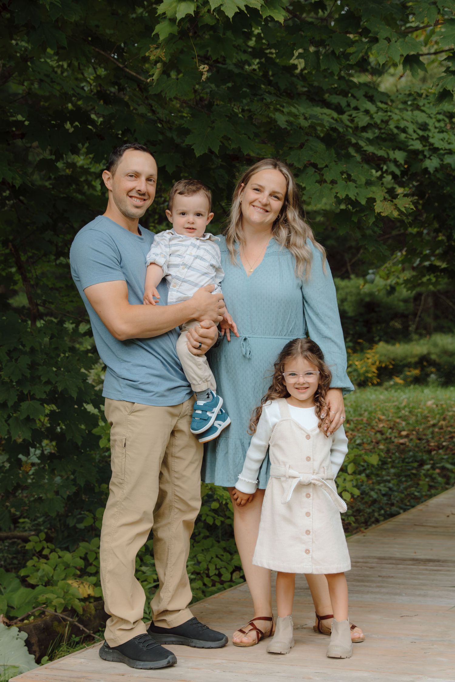 Family in coordinating blue and white outfits posing on outdoor walkway.
