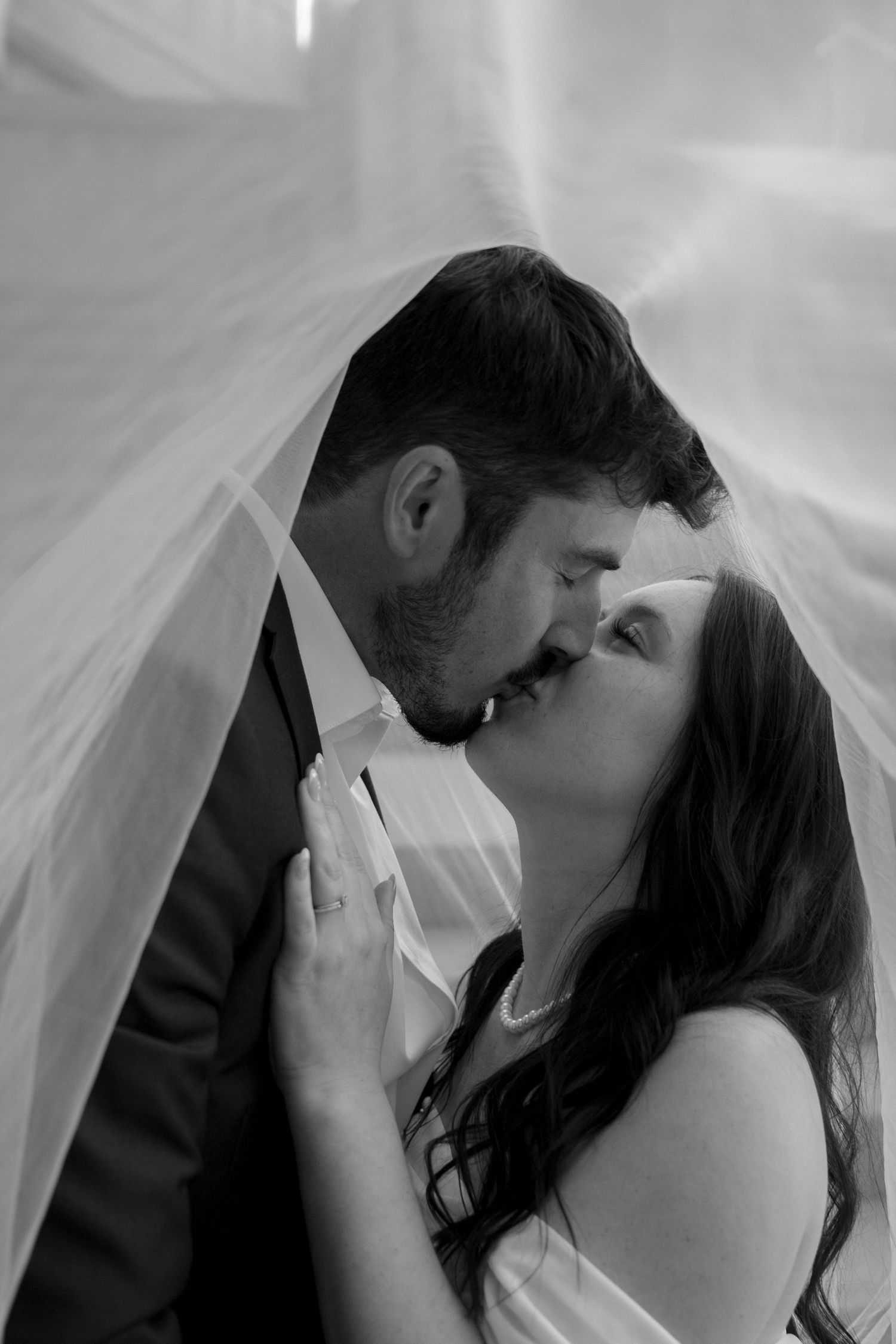 Romantic wedding kiss sequence under flowing white veil.